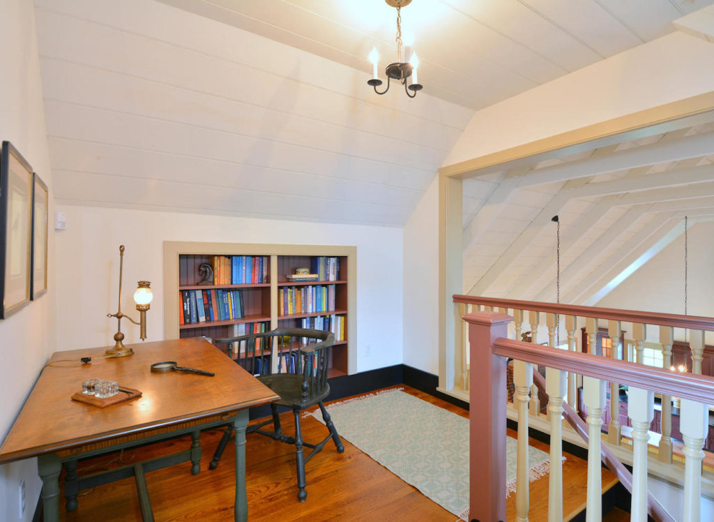 Loft area with desk and stairs leading down in an olde bulltown home