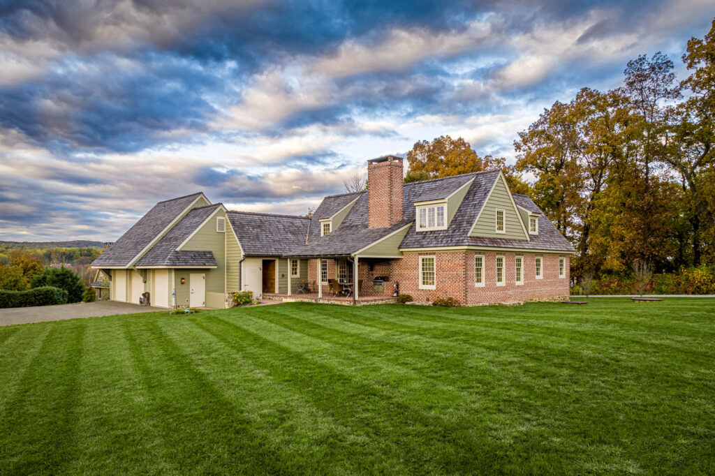 Front elevation of a brick home with green siding from olde bulltown